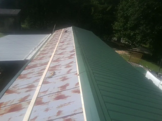 Old rusted panels beside newly installed green metal roofing — Wind Damage Roof Repair by Roofing Brothers in Kentwood