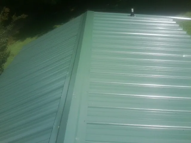 New green metal panels meeting at the ridge of a roof — Flat Roof Repair work by our crew in Kentwood