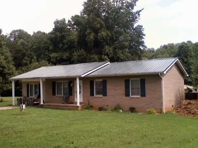 Gray metal roof on a brick ranch house with a side carport in Kentwood