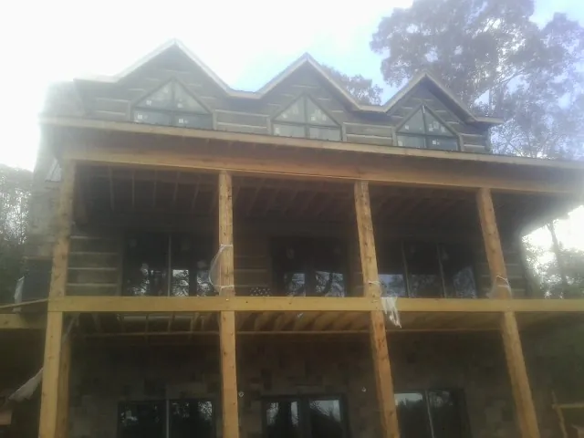 Dormers and porch framing on a large log home under construction — Roof Coating work by our crew in Kentwood