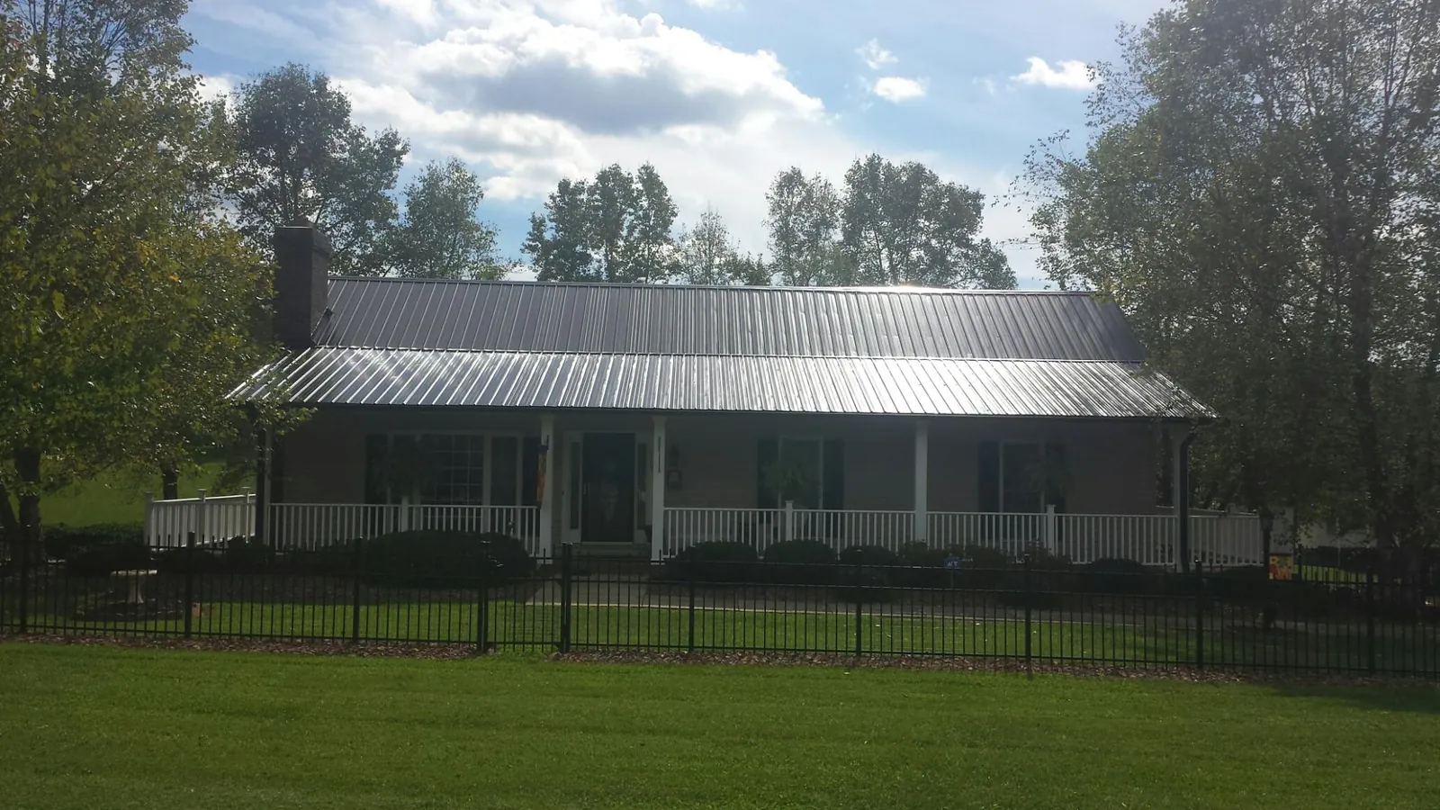 Gray metal roof on a brick ranch with a full width front porch — Gutter Guard Installation work by our crew in Kentwood