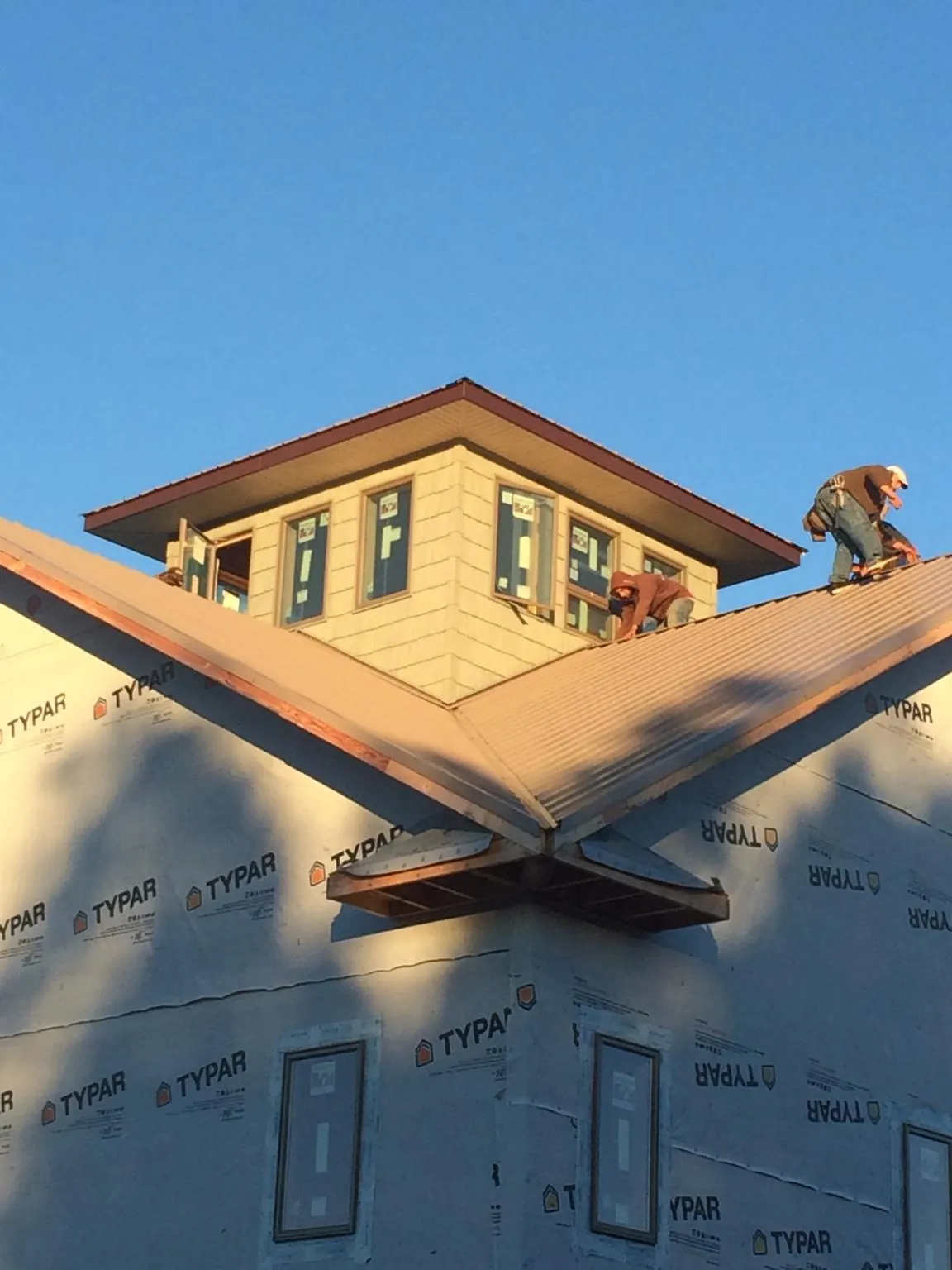 Roofers working around a rooftop cupola on a new metal roof at sunset — Roof Waterproofing in Kentwood by Roofing Brothers